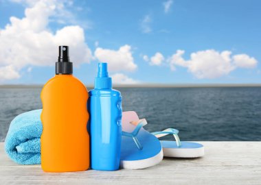 Güneş koruma vücut kremi ve plaj aksesuarları farklı şişe ile deniz manzarası karşı tablo ayarlama. Alan tasarımı için