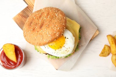 Düz ahşap arka plan üzerinde kızarmış yumurta ile lezzetli hamburger, lay