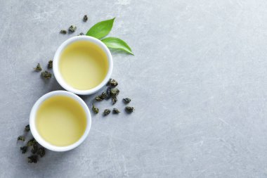 Kravat Guan Yin oolong ve çay yaprakları gri arka plan, metin için yer ile üstten görünüm üzerinde bardak