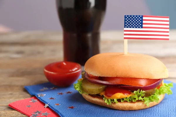 Burger and USA flag on wooden table, space for text. Traditional American food