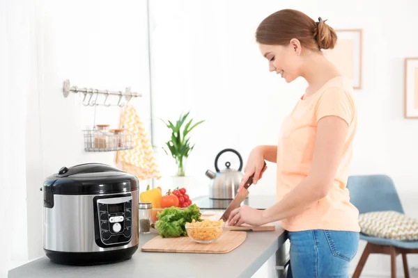 Jonge vrouw bereiden van voedsel in de buurt van moderne multi fornuis in de keuken — Stockfoto