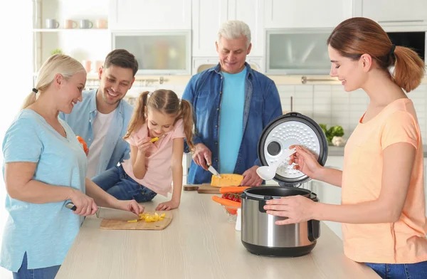 Happy family preparing food with modern multi cooker in kitchen — Stock Photo, Image