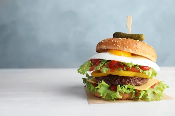 Chutné burger se sázeným vejcem na stole barvu pozadí, prostor pro text — Stock fotografie
