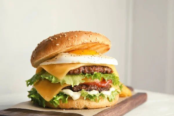 Смачне бургер зі смаженим яйцем на дошці на світлому фоні — стокове фото