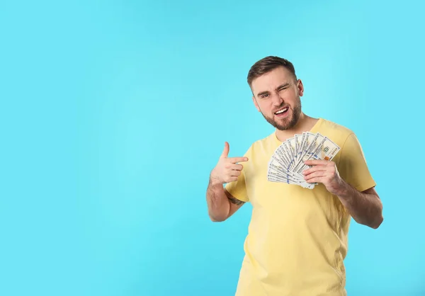 Portrait of happy young man with money on color background. Space for text — Stock Photo, Image
