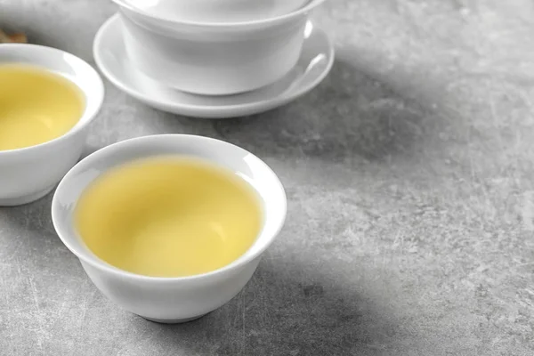 Xícaras de chá oolong acabado de fazer na mesa cinza. Espaço para texto — Fotografia de Stock