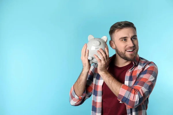 Joven feliz con alcancía y espacio para texto sobre fondo de color. Ahorro de dinero — Foto de Stock