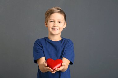 Sevimli çocuk ahşap kalp gri arka plan üzerinde tutan