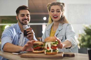 Mutlu genç çift burger restoranda öğle yemeği