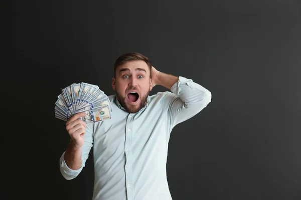 Portrait of emotional young man with money on grey background — Stock Photo, Image