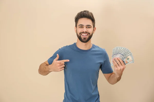Porträt eines glücklichen jungen Mannes mit Geld auf farbigem Hintergrund — Stockfoto