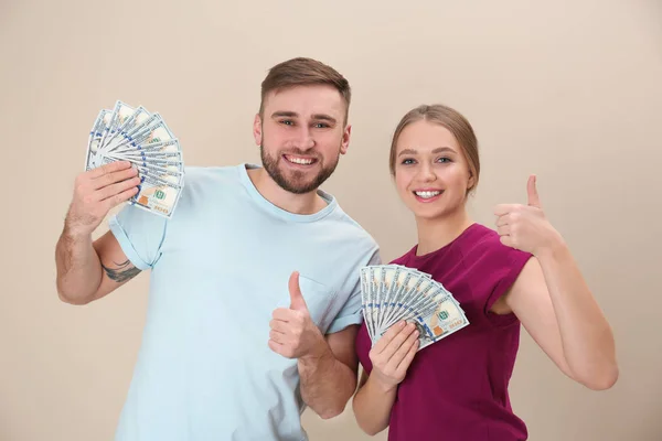 Счастливая молодая пара с деньгами на цветном фоне — стоковое фото