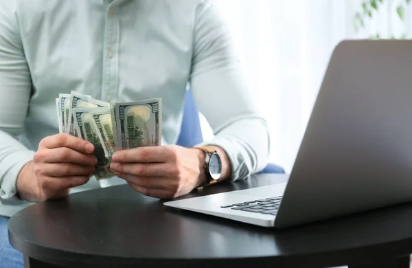 Бизнесмен с ноутбуком и деньгами за столом в помещении, крупным планом — стоковое фото