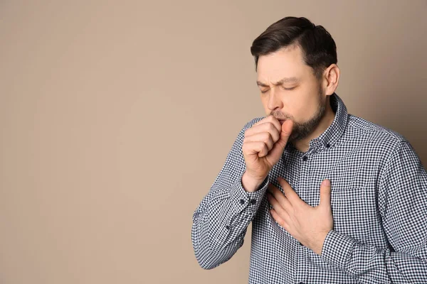 Hombre que sufre de tos en el fondo de color. Espacio para texto — Foto de Stock