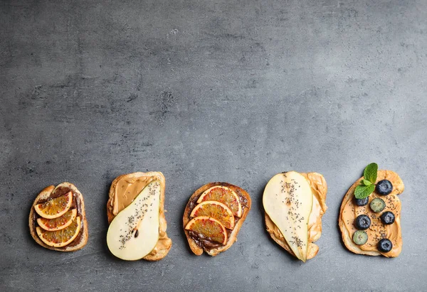 Verschillende toast met fruit, bosbessen en chia zaden op grijze achtergrond, top uitzicht. Ruimte voor tekst — Stockfoto