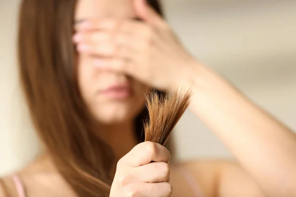 Emotionale Frau mit strapaziertem Haar auf verschwommenem Hintergrund, selektiver Fokus. Spliss — Stockfoto