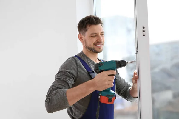 Trabajador de la construcción usando taladro mientras instala ventana en interiores — Foto de Stock