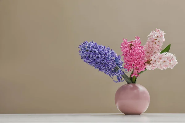 Красиві гіацинти у вазі на столі на кольоровому фоні, простір для тексту. Весняні квіти — стокове фото