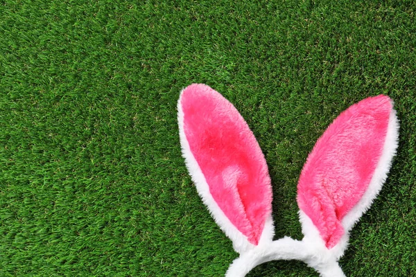 Funny headband with Easter bunny ears on green grass, top view. Space for text — Stock Photo, Image