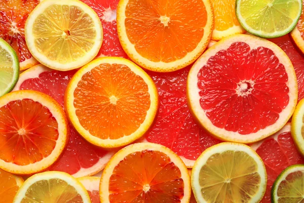Plastrami świeżych owoców cytrusowych, jako tło, widok z góry — Zdjęcie stockowe