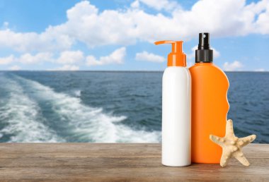 Güneş koruma vücut kremi farklı şişe ile deniz manzarası karşı ahşap tablo ayarlama. Alan tasarımı için