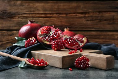 Olgun nar ve kaşıkla tohumlar üzerinde ahşap arka plan karşı tablo