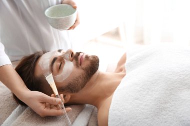 Spa salonu müşterinin yüzüne maske uygulayarak güzellik uzmanı
