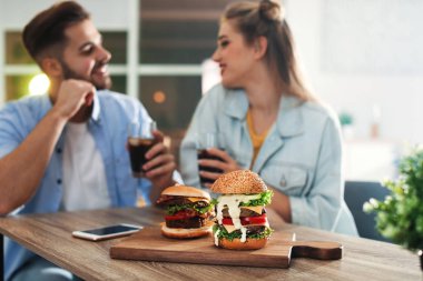 Genç çift restoranda hamburger ile gemide odak Öğle Yemeği