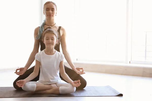 Mãe e filha praticando zen ioga no ginásio, espaço para texto — Fotografia de Stock