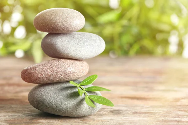 Piedras de spa y hojas de bambú sobre la mesa sobre fondo borroso, espacio para el texto. Zen, equilibrio, armonía — Foto de Stock