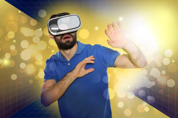 Homem emocional jogando jogos de vídeo em óculos de realidade virtual em fundo de cor — Fotografia de Stock