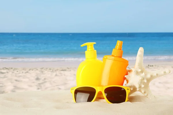 Bouteilles de crème solaire pour le corps et lunettes de soleil sur la plage de sable. Espace pour le design — Photo