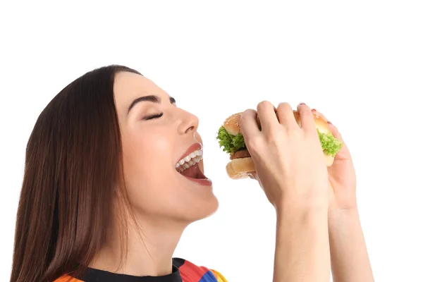 Young woman eating tasty burger on white background — Stock Photo, Image