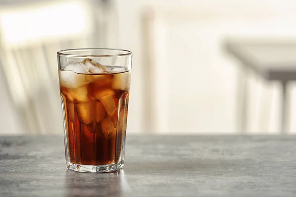 Vaso de cola con hielo sobre la mesa sobre fondo borroso, espacio para texto — Foto de Stock