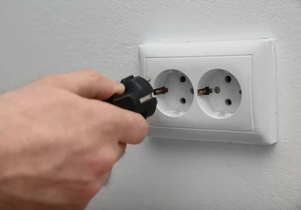 Eletricista inserindo plug em tomada de energia no fundo branco, close-up — Fotografia de Stock