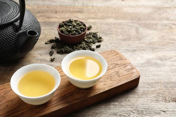 Tazze e teiera di cravatta Guan Yin oolong su tavolo di legno. Spazio per testo — Foto Stock