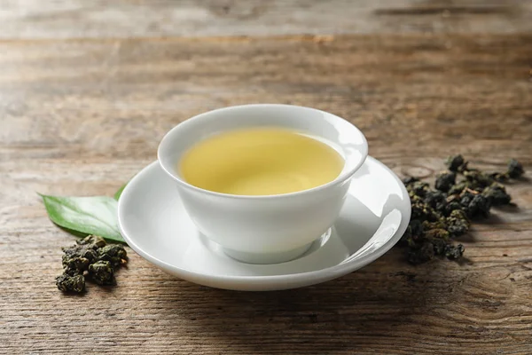 Cup Tie Guan Yin oolong en thee bladeren op houten tafel — Stockfoto