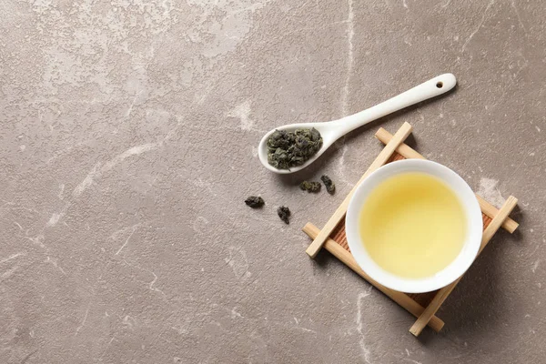 Cup of Tie Guan Yin oolong and spoon with tea leaves on table, top view. Space for text — Stock Photo, Image