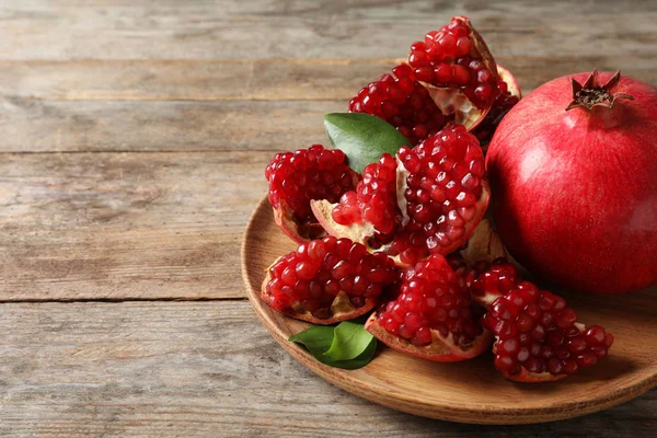 Piatto con melograni maturi e semi su fondo di legno, spazio per testo — Foto Stock