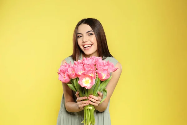 春チューリップ黄色の背景で美しい笑みを浮かべて少女の肖像画。国際女性の日 — ストック写真