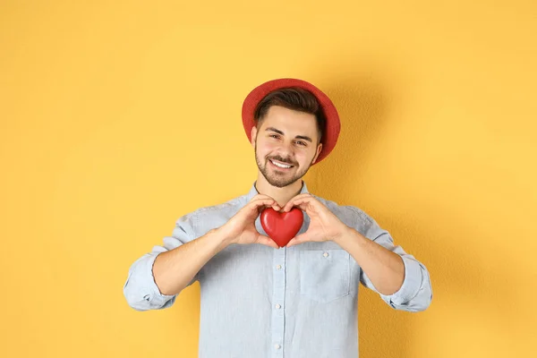Hombre sosteniendo corazón decorativo sobre fondo de color — Foto de Stock