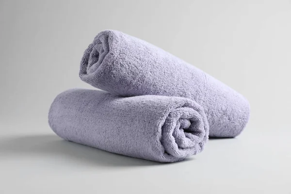 Fresh fluffy rolled towels on grey background