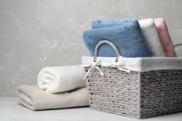 Плетеная корзина и свежие полотенца на столе — стоковое фото