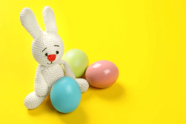 可爱的复活节兔子玩具和染色鸡蛋上的颜色背景, 文本空间 — 图库照片