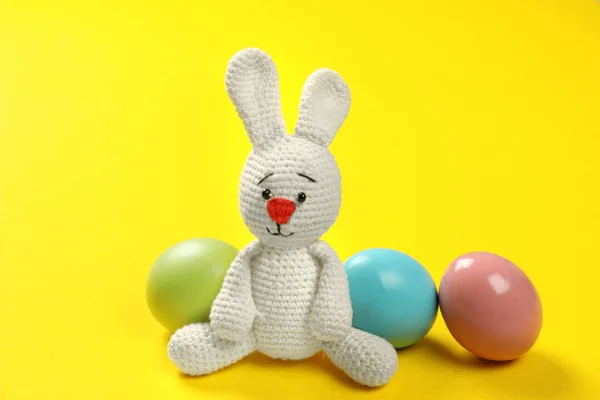 可爱的复活节兔子玩具和染色鸡蛋上的颜色背景 — 图库照片