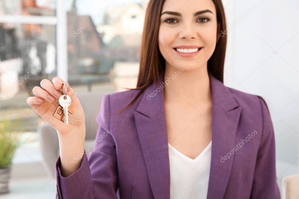 Young woman holding new house key indoors