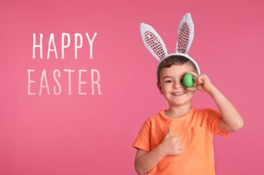 Eye yakınındaki yumurta renk arka plan üzerinde tutarak bunny kulaklar kafa bandı içindeki küçük çocuk. Mutlu Paskalya