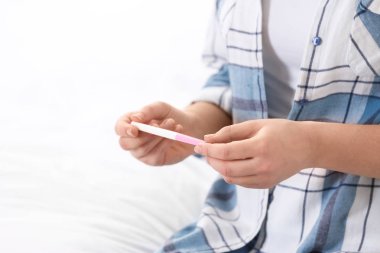 Genç kızla yatakta, closeup hamilelik testi. Metin için yer