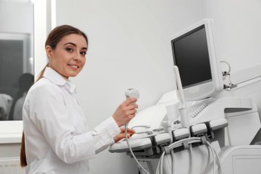 Professional sonographer using modern ultrasound machine in clinic clipart