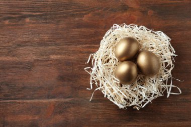 Ahşap arka plan, üstten görünüm üzerinde altın yumurta yuva. Metin için yer